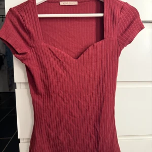 Röd ribbad topp från Anna Field - Snygg röd topp från Anna Field med ribbad struktur och mjukt bomullsmaterial. Toppen har korta ärmar, v-ringad hals och figurnära passform som framhäver siluetten❤️❤️