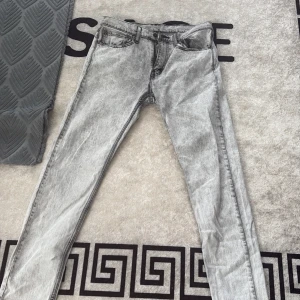 Levis 511 grå acid wash jeans W32 L32 - Snygga Levis 511 jeans i grå acid wash med klassisk femficksdesign och dragkedjegylf. Jeansen har en slim passform och är tillverkade i slitstarkt jeanstyg. Perfekta för dig som gillar en modern och edgy look.