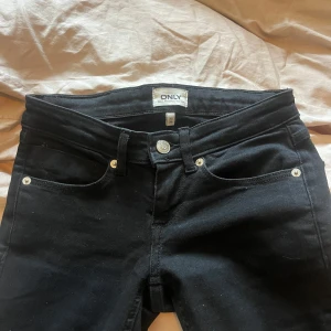 Svarta bootcut jeans från ONLY - Säljer ett par svarta bootcut jeans med slitz från ONLY. De har låg midja och stretchigt bomullsmaterial så det väldigt bekväma. Utsvängda ben och silverdetaljer vid fickorna. Skit snygga men för små för mig! Använts en eller två ggr 🩷