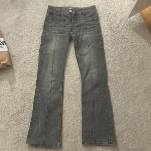 Grå bootcut jeans med fickor - Snygga grå jeans med bootcut passform och markerade sömmar längs benen. Byxorna har två stora fickor fram och klassiska bakfickor. Jätte snygga och säljs inte längre, säljer pga att de inte kommer till användning. Skicka om frågor💓