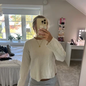 Vit stickad tröja med ribbade detaljer - Supermysig vit stickad tröja med rund hals och ribbade muddar vid ärmslut och nederkant. Tröjan har en relaxed fit och är perfekt för lager-på-lager. Enkel och stilren design som passar till allt.