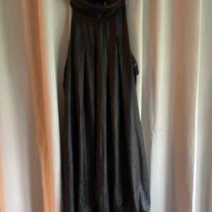 Svart klänning från Diesel - Säljer en svart klänning från Diesel i glansigt material. Klänningen har knytning i nacken och öppen rygg.