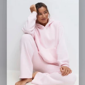 Mjukis sätt  - Supermjuk ljusrosa hoodie med huva och stor magficka. Oversized fit och långa ärmar, perfekt för chill dagar. Tillverkad i fleece som känns riktigt skön mot huden. Enkel och stilren design utan tryck eller mönster. Och fina rosa mjukis byxor 