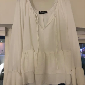 Vit volangblus från Missay - Superfin vit blus från Missay med volangdetaljer och långa ärmar. Blusen har v-ringning med knytband, knappast använd