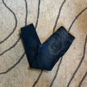 Replay jeans  - Snygga mörkblå jeans från Replay med klassisk femficksdesign och coola detaljer på bakfickan. Jeansen har raka ben och tydliga sömmar, samt knappar framtill. Perfekta för dig som gillar en tidlös och stilren look. Svåra att få tag på 