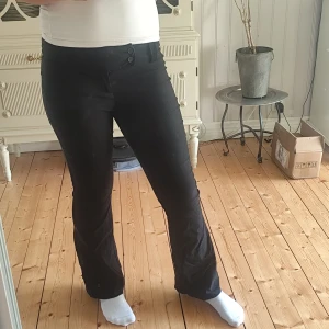 Svarta bootcut kostymbyxor - Svarta bootcut-byxor från Gina Tricot med sido knäppning i midjan. Snygg passform med utsvängda ben och klassisk look. Säljer då de inte kommer till någon användning men är i mycket bra skick. Använts cirka 2-3 gånger.