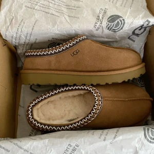 Uggs tasman  - UGG Slip-ons – Storlek 42 | Nästan nya!   Säljer ett par äkta UGG i storlek 42, nästan helt nya och bara provade några gånger. Supermjuka med fårskinnsfoder och den klassiska UGG-designen – perfekta för både hemmamys och vardagsbruk. Bra nu till höst och vinter :)   ✅ Storlek: 42 ✅ Skick: Nästan nya 💰Pris på: 929  📍 Kan hämtas eller skickas mot frakt.