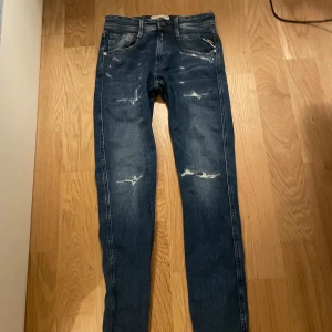 Replay Anbass slim fit jeans  - Feta Replay Anbass jeans i slim fit med slitna detaljer och tvättad blå färg. Slim passform som sitter riktigt bra. Sälja då de inte riktig var min stil och är använda max 2-3 gånger så riktigt bra skick. W27 L30