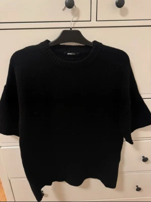 Svart stickad tröja Gina Tricot - Svart stickad tröja från Gina Tricot i storlek S. Stor i storleken!! Tröjan har rund hals och korta ärmar med ribbad kant vid halsen och ärmslut. Perfekt för lager-på-lager och enkel att matcha med jeans eller kjol.