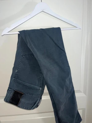 Gråa jeans från replay - Snygga gråa jeans från replay med klassisk femficksdesign och detaljerad söm på bakfickan. Jeansen har en rak passform och är tillverkade i slitstarkt jeanstyg. Läderpatch med replay-logga baktill ger en schysst touch. Jeansen är i storlek W32-L34