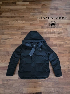 Canada Goose Macmillan Parka Black Label  - 🖤 Canada Goose Macmillan Parka Black Label 🖤 Exklusiv och mycket varm vinterjacka från Canada Goose i Black Label-utförande med svart emblem och stilren premiumdesign. Helt ny med tagg kvar.. Perfect för nordiskt klimat med tjock dunfyllning, skyddande huva och djupa dragkedjefickor. Dustbag ej med! En lyxig och praktisk vinterfavorit.  📦 Snabb leverans – skickas samma dag 📩 Skriv vid intresse