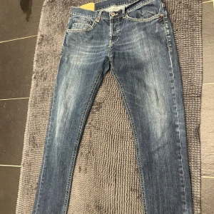 Dondup jeans George  - Snygga blå dondup  jeans med slim fit och klassisk femficksdesign. Jeansen har slitningar och kontrastsömmar, samt dondup logga på bakfickan. Passar dig som gillar en modern och smal siluett. Materialet är slitstarkt jeans i bomull. Storlek 33, passar 32,31