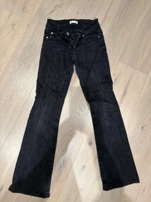 Svarta bootcut jeans från Gina Tricot stl 34 - Svarta jeans från Gina Tricot med bootcut-snitt och klassisk femficksdesign. Byxorna är i skön stretch, normal midja, dragkedja och knapp framtill. Materialet är jeans med en lätt tvättad look.