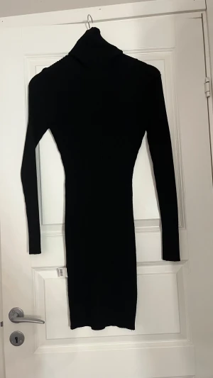 Svart ribbad poloklänning - Säljer en svart, ribbad klänning med polokrage och långärmade ärmar. Klänningen är figurnära och har en kort längd som ger en snygg siluett. Perfekt för dig som gillar stilrena och enkla plagg med lite edge.