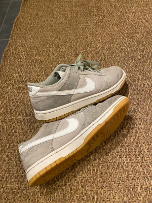 Nike Dunk Low i grön mocka - Nike Dunk Low sneakers i ljusgrön mocka. Yttersulan är i gummi med en  brun ton. Perfekta för dig som gillar stilrena och klassiska sneakers med en soft vibe. Inköpt från zalando 1500 säljer för 600