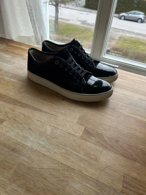 Lanvin cap toe svarta med box och dustbag - Säljer ett par svarta sneakers från Lanvin. Ingår både låda och dustbag med dessa dojor. Skorna är i storlek 8 us eller i 42 eu. Skorna är i riktigt bra skick och använts väldigt sparsamt. Lacken är nästintill orepad och mockan är bra. Vid minsta lilla fråga så är de bara att höra av sig!