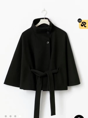 Svart kappa med bälte och vida ärmar - Stilren svart kappa med högt krage, knappar framtill och ett matchande bälte i midjan. Mycket bra skick använd fåtal gånger. Kappan är slutsåld på Gina Tricot !