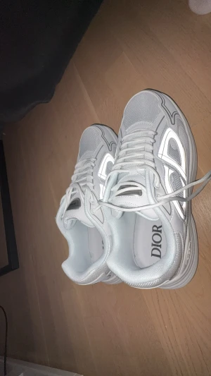 Dior B30 vita sneakers.        OBS BOX INGÅR BARA VID FULLPRIS  - Säljer ett par fräscha Dior B30 sneakers i vitt med silvriga detaljer. Skorna har en chunky sula, mesh och skinnpaneler samt snörning framtill. Reflekterande inslag på sidorna och tydlig Dior-logga på plösen. Tillverkade i Italien och riktigt snygga till streetwear.