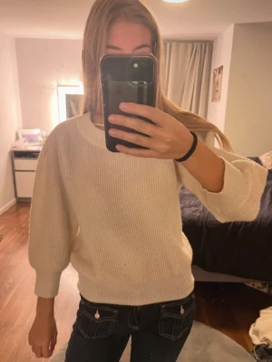 Vit stickad tröja med ballongärm - Mysig vit stickad tröja med rund hals och ballongärmar. Tröjan har en ribbad struktur och är perfekt för kyliga dagar. Passformen är normal och materialet känns mjukt mot huden. Enkel att matcha med jeans eller kjol för en chill look.