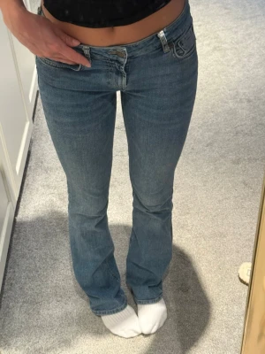 Bootcut jeans från Zara, ljusblå - Snygga ljusblå bootcut jeans från Zara i storlek 36. Modellen är lågmidjad med klassisk femficksdesign och dragkedja med knapp. Jeansen har en lätt utsvängd passform nedtill och är tillverkade i mjukt bomullsmaterial med lite stretch för extra komfort.