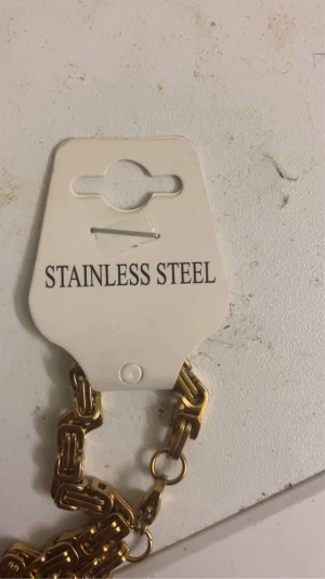 Guldfärgad kedja i rostfritt stål - Säljer en helt ny guldfärgad kedja i rostfritt stål med ett chunky och stilrent länkformat mönster. Kedjan har en snygg glans och känns rejäl runt halsen, perfekt för dig som gillar att sticka ut med accessoarer. Passar till både street och casual stil.