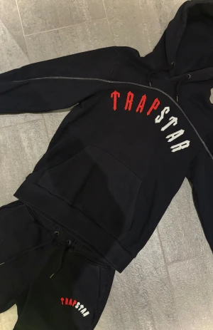 Trapstar Irongate Arch Chenille set (tracksuit, hoodie + mjukisbyxor)  - Äkta Trapstar set (storlek M) för herr med broderat rött och vitt tryck🧯 Kvitto kan fixas vid intresse🧾 Materialet är mjukt och bekvämt, perfekt för chill eller streetwear🚏Setet är i väldigt fint skick och har knappt använts⚠️ Skriv vid frågor. Pris kan diskuteras🫱🏻‍🫲🏾