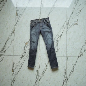 Replay Anbass - Aldrig använda snygga helt nya Replay Anbass jeans i slim fit med klassisk femficksdesign och mörkblå tvätt. Jeansen har kontrastsömmar, bälteshällor och en vit Replay-logga på bakfickan. Materialet är jeans med återvunnen bomull för extra komfort.