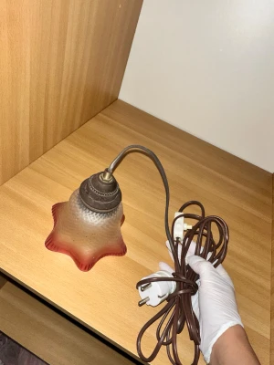 lampa med rosa detaljer - En fin lampa med stjärnformad glasskärm i rödrosa ton och brun sladd.En charmig bordslampa med en unik design. Lampan har en rosa nyans som ger ett mjukt och behagligt ljus. Perfekt som stämningsbelysning i vilket rum som helst.