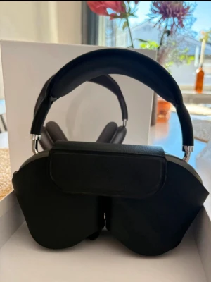 AirPods Max - Snygga och välbevarade Apple AirPods Max i svart/grå färg. Over-ear design med mjuka kuddar och robust bygelfäste. Levereras med originalfodral och laddningskabel. Inga synliga repor eller skador, ser ut att vara i mycket gott skick. Perfekt för högkvalitativ musik och brusreducering.
