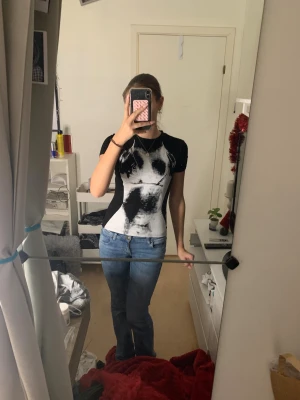 Svart och vit tight topp med tryck❤️‍🔥 - Säljer en svart och vit topp med korta ärmar och ett unikt abstrakt tryck framtill. Modellen är tight och figurnära, med rund hals och helsvart baksida. Materialet känns mjukt och stretchigt, troligen bomull eller polyester. Perfekt för dig som gillar edgy och coola prints.❤️‍🔥