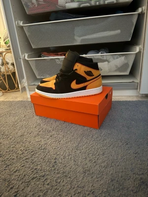 Air Jordan 1 Mid svart/gul - Säljer ett par Air Jordan 1 Mid i svart och gul mocka och läder. Klassisk siluett med vit sula och svart swoosh. Skorna har ikoniska Jordan Wings-loggan på sidan och Jumpman på plösen. Perfekta för dig som vill sticka ut med snygga färger och streetwear-vibe. De är helt nya och knappt använda kanske 2 gånger max. Skriv gärna för frågor och skicka gärna bud !😁
