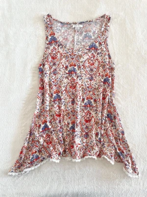 Amisu mönstrad ärmlös topp - Ett fint vitt linne med ett paisley mönster i rött, blått, lila och beige, den har spetskant nedtill och är gjort av ett mjukt material, har inga defekter