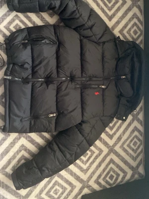 Svart dunjacka från Polo Ralph Lauren - Den kom i fel storlek därför Säljer min nya Snygg svart dunjacka från Polo Ralph Lauren med röd logga på bröstet. Jackan har flera dragkedjeförsedda fickor, hög krage och huva. Perfekt för kalla vinterdagar. Pris kan diskuteras 