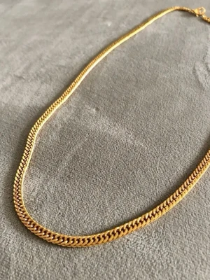 Pansarlänk i 18k guldplätering, 50 cm - Pansarlänk i rostfritt stål med guldplätering i 18k guld. Kedjan är 4 mm bred och 50 cm lång. Oanvänd och i perfekt skick då den kommer från en nedlagd butik.  Se även mina övriga annonser. Jag samfraktar givetvis.