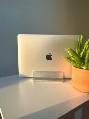 Stilren laptopställ i aluminium - Säljer ett snyggt och minimalistiskt laptopställ i silverfärgad aluminium. Perfekt för att hålla din laptop upprätt på skrivbordet och spara plats. Passar de flesta bärbara datorer och ger ett modernt intryck till din setup.