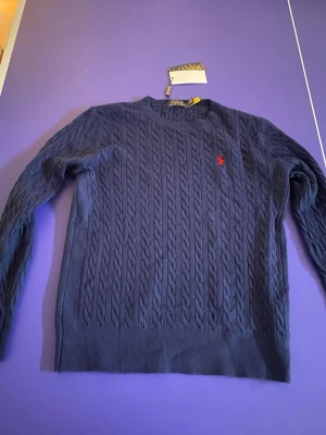 Sweater Polo Ralph Lauren Cable Knit 🧥the sweater is a bit smaller then s  - This is a navy blue cable knit sweater from Polo Ralph Lauren. It appears brand new with tags still attached.  ⭐️ Condition: 10/10 🎨 Color: Navy Blue 📦 Fast and careful shipping