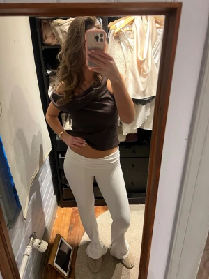 Vita bootcut yogapants - Säljer ett par vita yogapants med bootcut-ben. Byxorna är stretchiga och sitter tajt upptill men släpper ut vid vaden. Materialet är mjukt och följsamt, troligtvis polyester eller bomullsmix. 💕