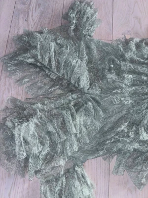 Ljusgrön volangklänning i spets - Romantisk ljusgrön klänning med flera lager volanger och spetsdetaljer. Klänningen har v-ringad hals, korta ärmar och är tillverkad i ett tunt, skirt material som ger en drömmig känsla. Perfekt för dig som vill sticka ut med en unik look.