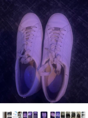 Vita sneakers från Michael Kors - Säljer ett par klassiska vita sneakers från Michael Kors med diskret logga på plösen och sidan. Skorna har vita snören, låg profil och ovandel i slätt läder med subtil struktur. Perfekta för en clean och stilren look.