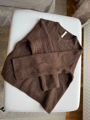 Brun stickad tröja från Lindex - Mysig brun stickad tröja från Lindex med rund halsringning och ribbade detaljer. Tröjan har en avslappnad passform och långa ärmar. Perfekt för lager på lager och höstmys. Materialet känns mjukt och värmande.