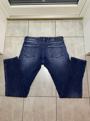 Mörkblå Replay Anbass jeans - Snygga mörkblå Replay Anbass jeans med femficks design. Jeansen har normal passform och raka ben, tillverkade i mjukt bomullsjeansmaterial för en skön och lite töjbar style. Perfekta för en avslappnad och stilren look. Vid frågor och funderingar hör gärna av dig! 