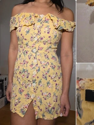 Gul blommig off-shoulder klänning - Söt gul off-shoulder klänning från Topshop med volangkant upptill och knappar framtill. Klänningen har ett blommigt mönster i rosa, lila och grönt samt en liten slits framtill. Perfekt för sommarens alla tillfällen.