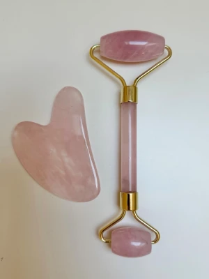 Ansiktsroller & gua sha - Säljer ett set med ansiktsroller och gua sha i ljusrosa rosenkvarts. Rollern har två stenar i olika storlekar och guldfärgade detaljer. Perfekt för ansiktsmassage och hudvård. Materialet är polerad rosenkvarts. Använd en gång🩷