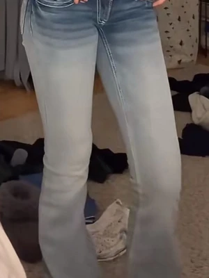 Ljusblå bootcut jeans med utsvängda ben - Säljer ett par ljusblå bootcut jeans med utsvängda ben och klassisk femficksdesign. Jeansen har en snygg tvätt med slitningar och markerade sömmar. Perfekta för dig som gillar en retroinspirerad look och vill ha ett par jeans som sticker ut. Helt nya med prislapp kvar