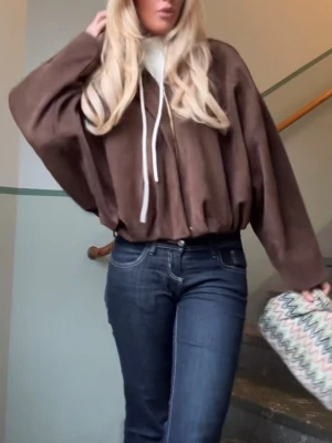 Brun oversized jacka med dragkedja - Säljer en brun oversized jacka med dragkedja och breda ärmar. Jackan har en avslappnad passform och är tillverkad i ett mockaliknande material. Perfekt för lager-på-lager och har en cool streetstil.