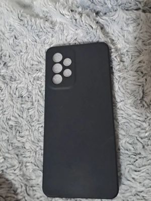 Svart mobilskal med kamerahål - Snyggt svart mobilskal med fem hål för kameror och blixt, perfekt för dig som vill skydda din mobil och samtidigt ha en stilren look. Skalet är gjort i ett mjukt och flexibelt material som känns skönt i handen och ger bra grepp.