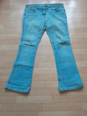Ljusblå bootcut jeans - Säljer ett par lågmidjade ljusblå bootcut jeans. Mått: Längd: 99 cm, Gren: 79 cm, Midja: 47 cm, Innersöm: 25 cm. 