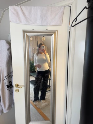 Svarta spetsbyxor loungewear - Säljer mina svarta spets byxor från design by si med utsvängda ben i genombruten spets. De har hög midja och ett trendigt mönster som ger en cool look. Perfekta för dig som vill sticka ut lite extra! Materialet är stretchigt och bekvämt. De är aldrig använda!