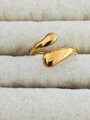 Extra ring på köpet 🧿 - Säljer två snygga ringar i guldpläterad metall. Den ena ringen har en öppen, droppformad design medan den andra har ett öppet hjärta med en lite ojämn, handgjord känsla. Perfekta för dig som gillar trendiga och personliga accessoarer.