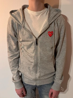 Comme des Garçons Play zip hoodie - | Skick: 7/10 | Färg: Grå | Modell: 175cm, 62kg | Vad inkluderas: Enbart hoodien | Nypris: 3 499kr | 